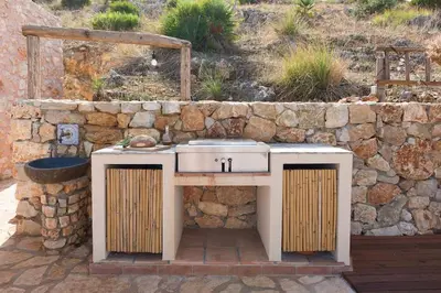 a outdoor kitchen with a stone wall and a sink at Villa Mori Cala Bianca in Castellammare del Golfo