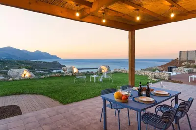 a table on a patio with a view of the ocean at Villa Disa Cala Bianca in Castellammare del Golfo