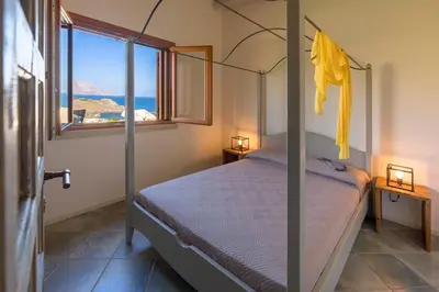 a bedroom with a canopy bed and a window at Villa Disa Cala Bianca in Castellammare del Golfo