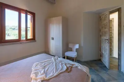 a bedroom with a bed and a window and a chair at Villa Disa Cala Bianca in Castellammare del Golfo