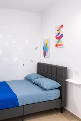a bedroom with a bed with blue sheets and paintings at Giancos apartment in Palermo