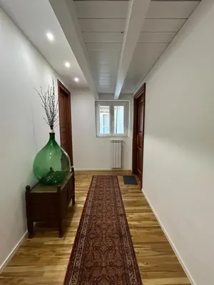 a hallway with a large green vase on a table and a rug at Appartamento Palermo Sole di Sicilia in Palermo