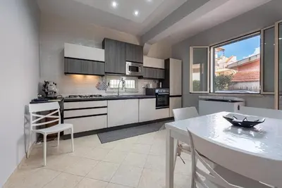 a kitchen with white cabinets and a table and chairs at Villino Giovanna a Trabia a 200 mt dal mare in Trabia