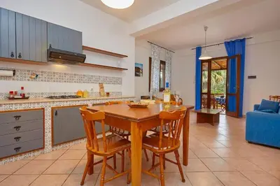 a kitchen with a wooden table and some chairs at Villa Capreria by Sicily Travelling Villas in Scopello