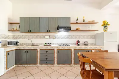 a kitchen with a wooden table and a kitchen counter top at Villa Capreria by Sicily Travelling Villas in Scopello