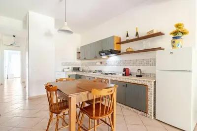a kitchen with a wooden table and a white refrigerator at Villa Capreria by Sicily Travelling Villas in Scopello