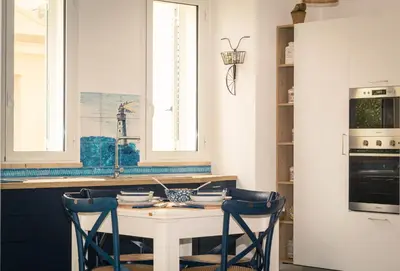 a kitchen with a white table and two blue chairs at Residence Spiaggia Centro - Aria Condizionata Wi-Fi&SelfCheck-In - Sole&Mare Home in Balestrate