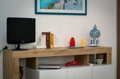 a tv sitting on top of a wooden shelf at Residence Spiaggia Centro - Aria Condizionata Wi-Fi&SelfCheck-In - Sole&Mare Home in Balestrate