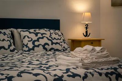 a bed with a blue and white blanket and a lamp at Residence Spiaggia Centro - Aria Condizionata Wi-Fi&SelfCheck-In - Sole&Mare Home in Balestrate
