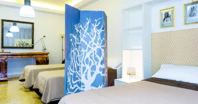 a bedroom with two beds and a blue and white curtain at Suite in Center Apartments in Palermo