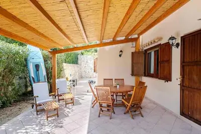 a patio with a wooden ceiling and a table and chairs at Villa Marinella by Sicily Travelling Villas in Scopello