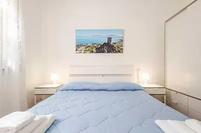 a white bedroom with a large bed with two lamps at Villa Marinella by Sicily Travelling Villas in Scopello
