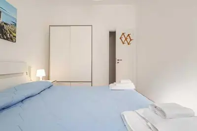 a white bedroom with a large bed and a door at Villa Marinella by Sicily Travelling Villas in Scopello