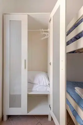 a white bunk room with a bed and a mirror at Villa Marinella by Sicily Travelling Villas in Scopello
