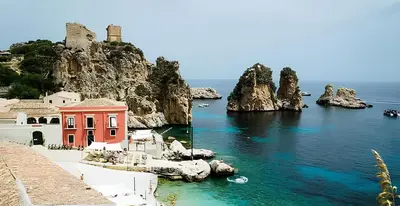 a view of the amalfi coast with a red building at Villa Uzzo by Sicily Travelling Villas in Scopello