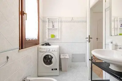 a white bathroom with a washing machine and a sink at Villa Varo by Sicily Travelling Villas in Scopello