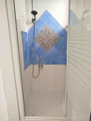 a bathroom with a shower with blue tile at Le Mura Home in Palermo