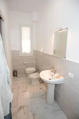 a bathroom with a sink and a toilet and a mirror at Azzurro Mare in Isola delle Femmine