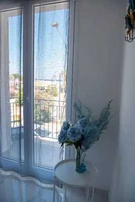 a vase of flowers on a table in front of a window at Azzurro Mare in Isola delle Femmine