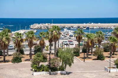 a parking lot with palm trees and a marina at Azzurro Mare in Isola delle Femmine