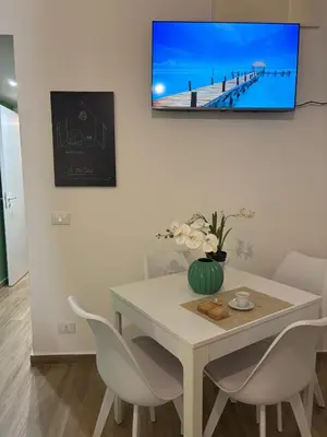 a dining room with a table and a tv on the wall at A me casa in Palermo
