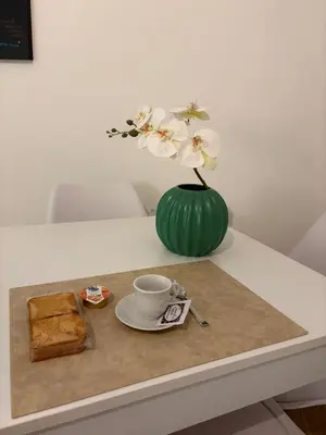 a table with a green vase with white flowers and a plate at A me casa in Palermo