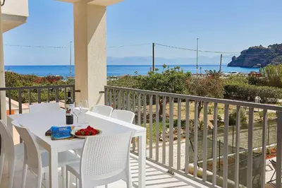a white table and chairs on a balcony with the ocean at Le Residenze di Zio Toto' in Scopello