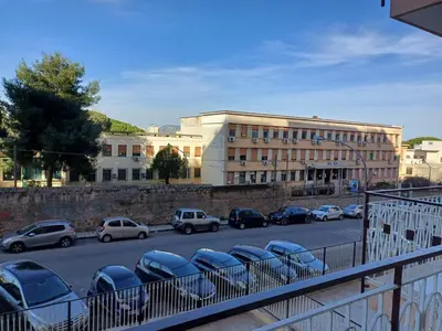 a parking lot with cars parked in front of a building at Villa Tàsca Apartment in Palermo