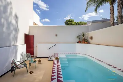 a swimming pool with two chairs next to a house at Verosicily Villa Damus in Terrasini