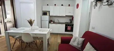 a white kitchen with a white table and a red couch at Cozy Apartment with Stunning Mountain Views in Lascari