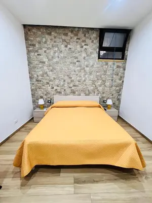 a bedroom with a yellow bed with a brick wall at Casa Vacanze di Maria in Palermo