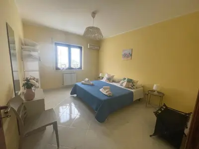 a bedroom with a blue bed and yellow walls at Sicily Holiday Home in Termini Imerese