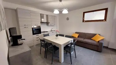 a kitchen and living room with a table and a couch at Casa Vacanza Ciglietti in San Vito lo Capo