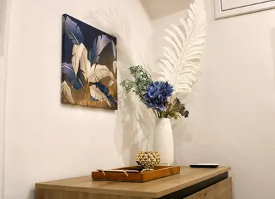 a vase of flowers on a table with a painting at Pillis House, accogliente appartamento in centro città, vicino al Politeama Palermo in Palermo
