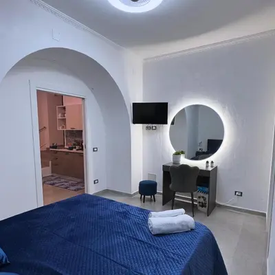 a bedroom with a bed and a desk and a mirror at Palermo Holiday Room in Palermo