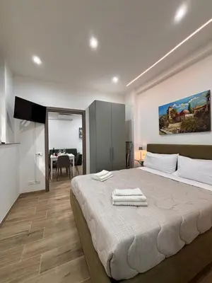 a bedroom with a large bed and a dining room at Garzilli Cozy Apartment in Palermo