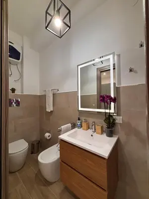 a bathroom with a sink and a toilet and a mirror at Garzilli Cozy Apartment in Palermo