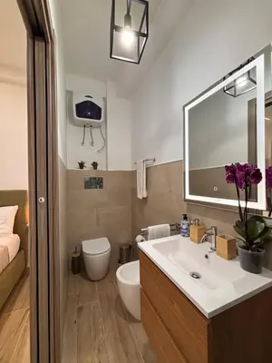 a bathroom with a sink and a toilet and a mirror at Garzilli Cozy Apartment in Palermo