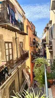 an alley with clothes hanging on the balconies of buildings at Fajra house in Palermo
