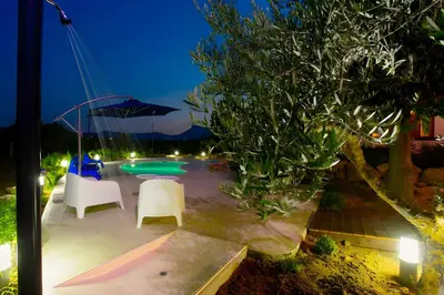 a patio with chairs and a pool at night at Villa Due Pini con piscina privata in Alcamo