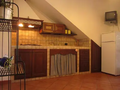 an attic kitchen with wooden cabinets and a refrigerator at Oasi del Sole- sun and sea - Casa Xenia in San Vito lo Capo