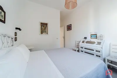 a white bedroom with a bed and a dresser at Grande e Luminosa Villa con Piscina vicino al Mare in Terrasini