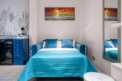 a bedroom with a bed with blue sheets and a painting at D'ossuna66 Classic in Palermo