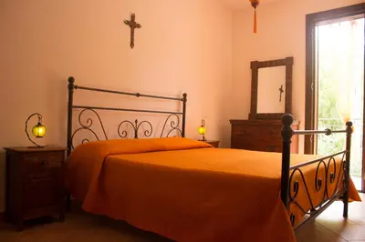 a bedroom with a bed and a cross on the wall at Oasi del Sole - sun and sea -Casa Colombo in San Vito lo Capo