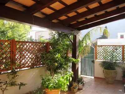 an outdoor patio with plants and a wooden pergola at Oasi del Sole - sun and sea -Casa Colombo in San Vito lo Capo
