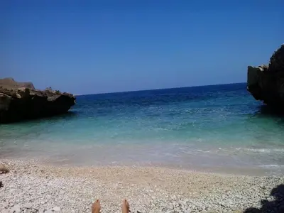 a person sitting on a beach near the water at Oasi del Sole - sun and sea -Casa Colombo in San Vito lo Capo