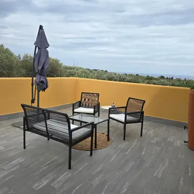 three chairs and a table and an umbrella on a roof at Villa Orlando in Trabia