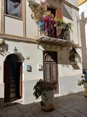 a building with a door and a balcony with flowers at Piliero room in Palermo