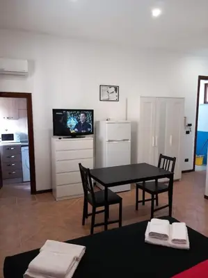 a living room with a table and chairs and a tv at Piliero room in Palermo