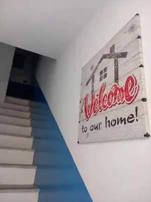 a sign that reads welcome to our home next to a staircase at Piliero room in Palermo